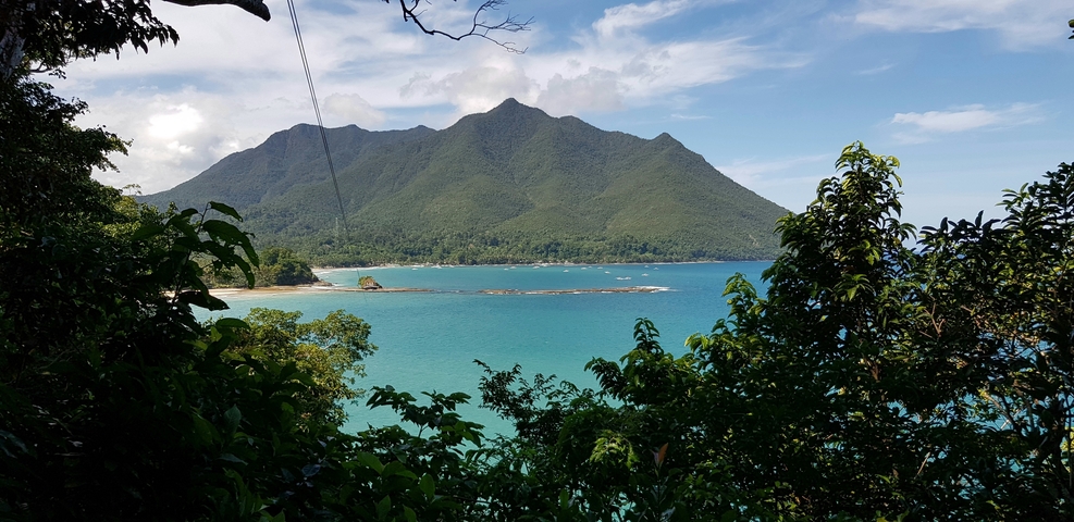       Coastal view with turquoise water and mountain backdrop.
  