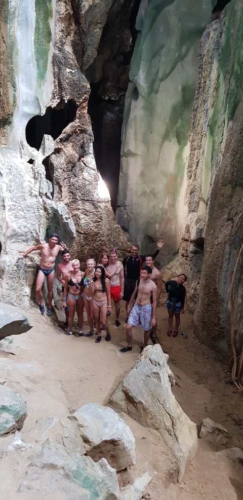       Group of tourists posing inside rock formations.
  