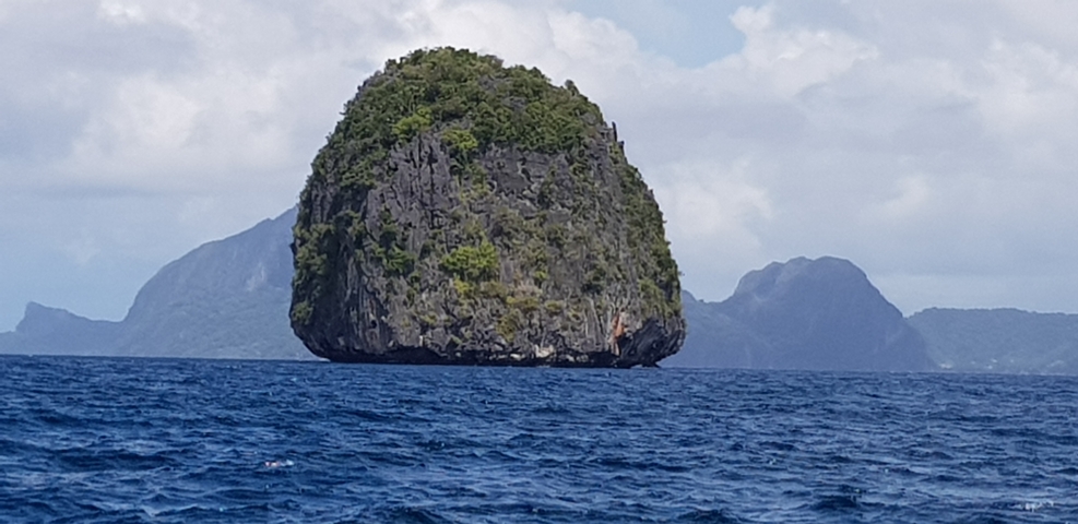       Distinctive island rock formation in clear ocean waters.
  