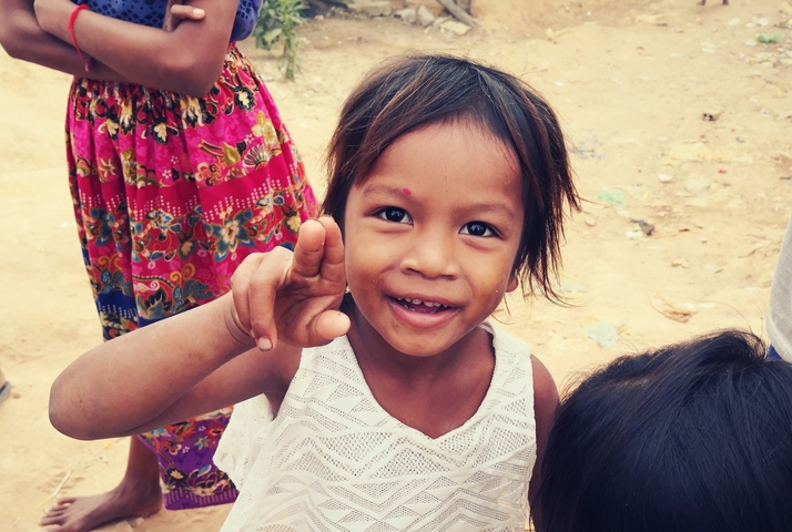 Smiling child making a gesture with hand.