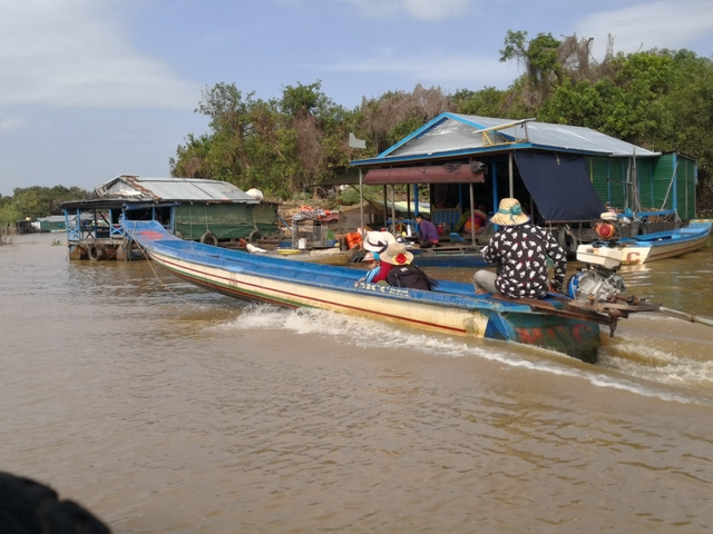 Two people on a boat in a floating village.