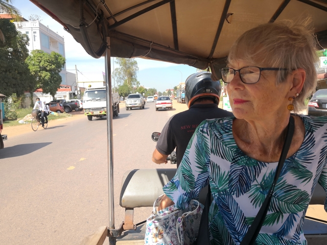       Elderly woman enjoying a tuk-tuk ride through the city.
  