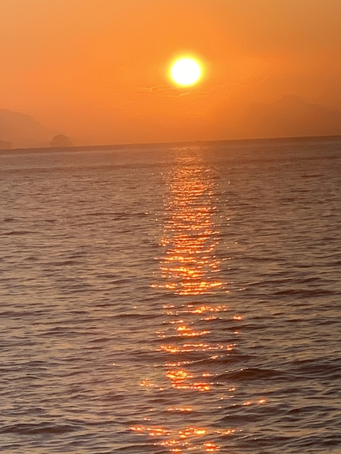 Sunset over the ocean with reflection on water.