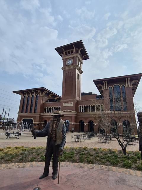 Clocktower with statue located in an urban setting.
