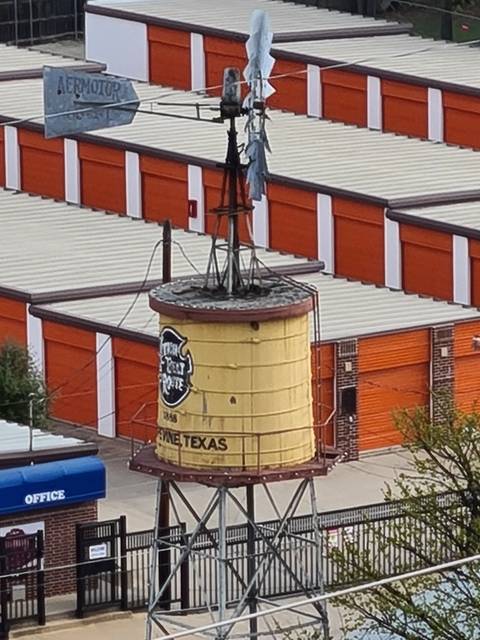 Water tower with Texas themed sign in urban area.