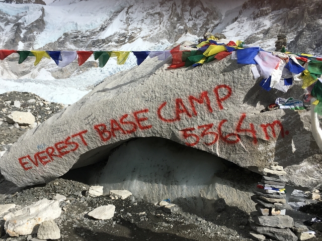       Rock with 'Everest Base Camp' inscription surrounded by colorful flags.
  