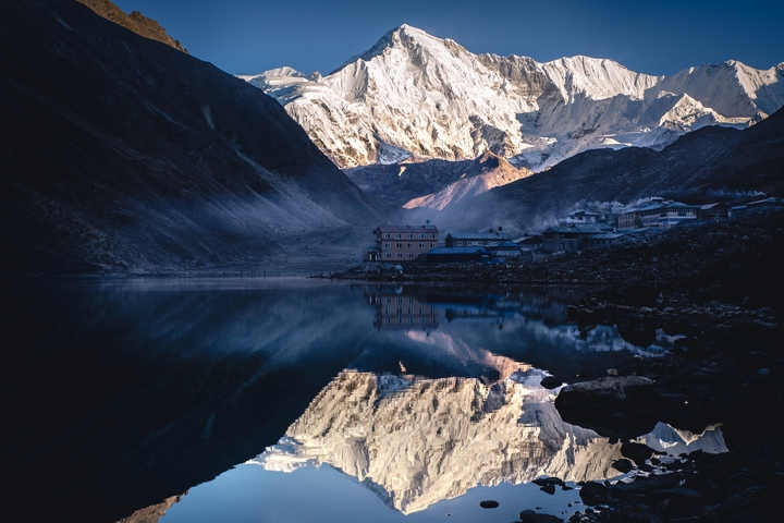       Snowy mountain range reflecting onto a lake at dawn.
  