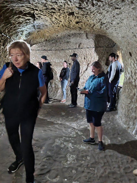       Tourists exploring an ancient cave with natural rock formations.
  