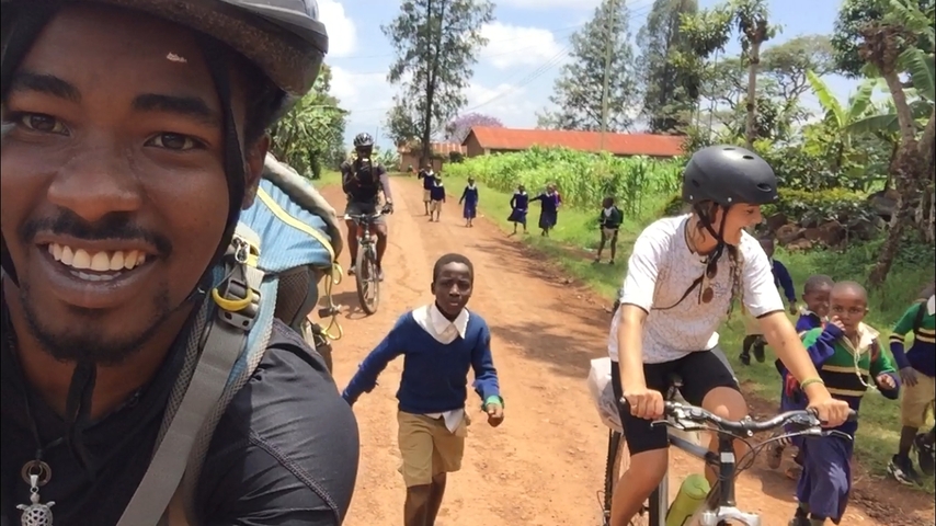       Cyclists interacting with children on a rural road.
  