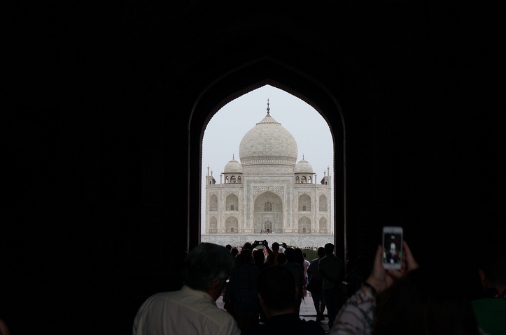 Silhouette of Taj Mahal framed by an archway with tourists.
