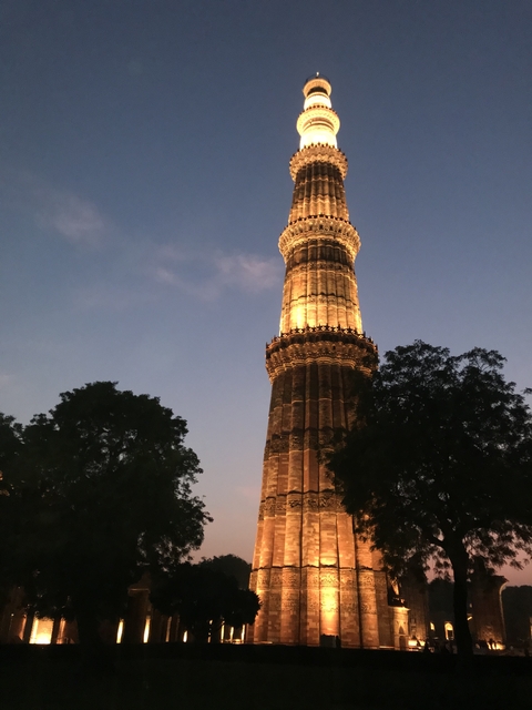 Lit Qutub Minar against the evening sky.