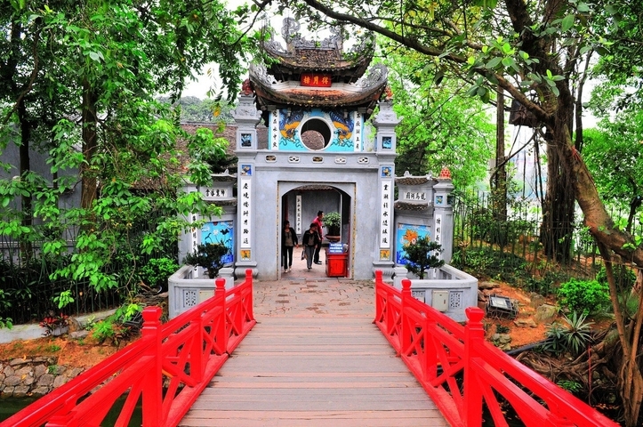 Entrance to Ngoc Son Temple with a red bridge and greenery.