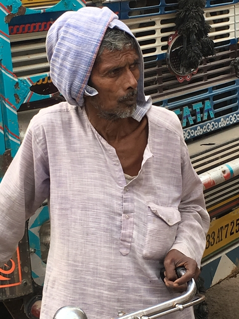 Close-up of an elderly man in front of a truck with TATA branding.