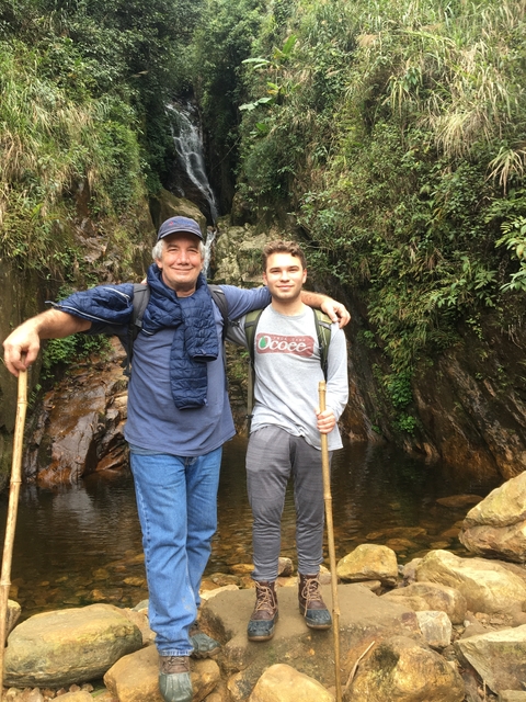       Two people with hiking gear posing in a forest setting.
  
