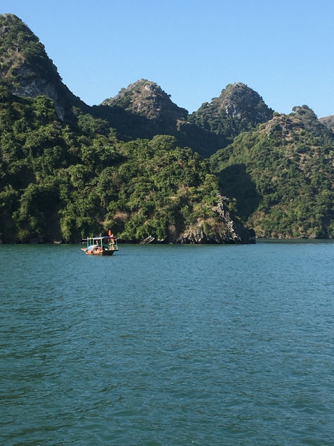       Small boat on a lake surrounded by lush green hills.
  