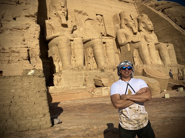 Person posing in front of ancient Egyptian statues.