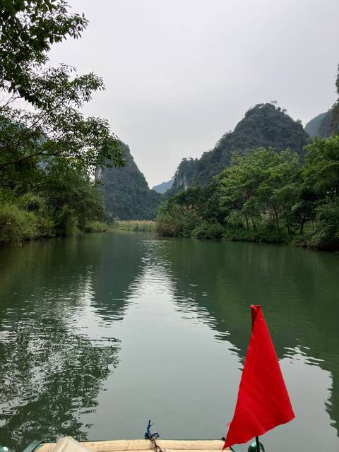       Serene view of a river with trees and a red flag.
  