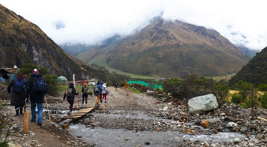 Group of hikers on a rocky path with mountains shrouded in mist.