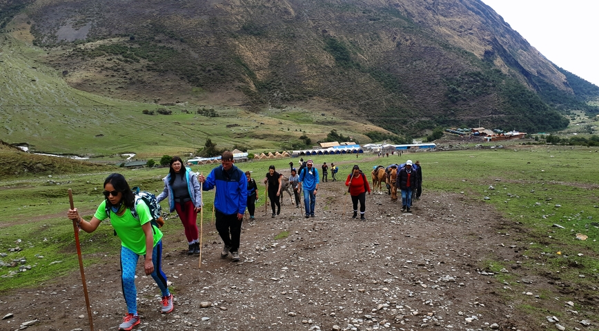 Hikers ascending a mountain trail with lush green vegetation.