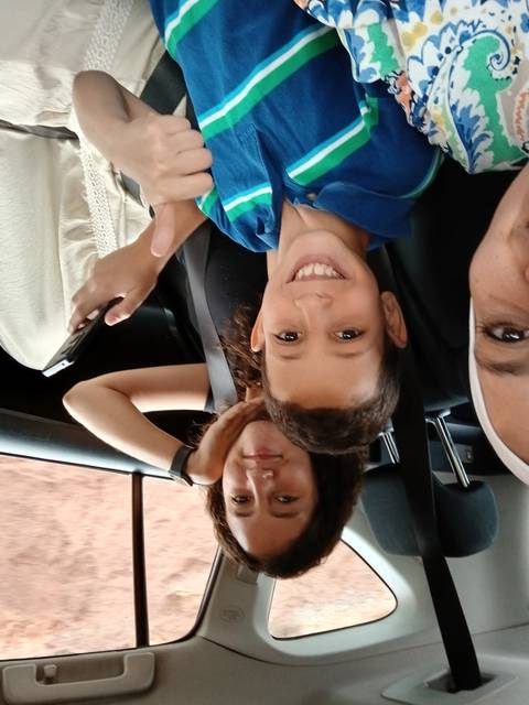       Two children in a car, smiling at the camera.
  