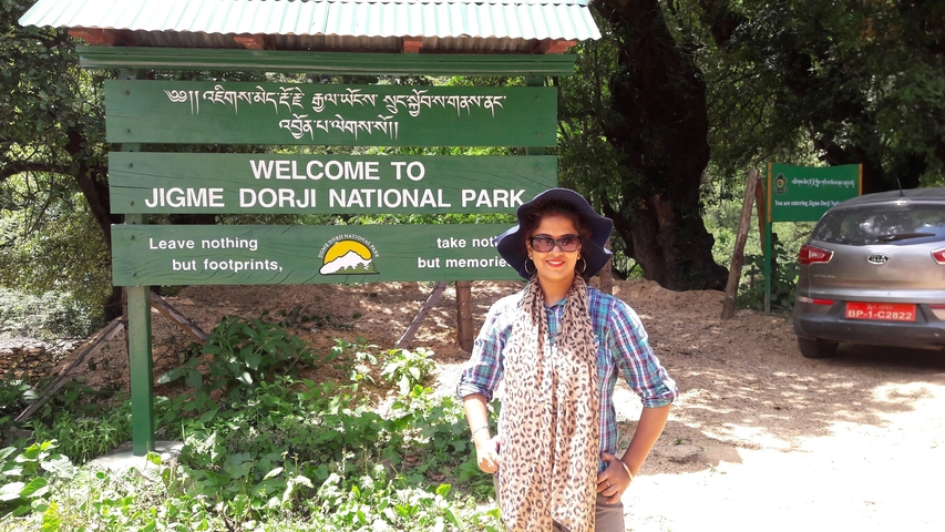       Person posing in front of a national park sign.
  