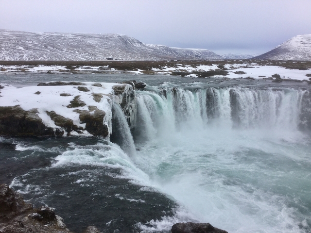 A waterfall cascading in a snowy mountainous landscape.