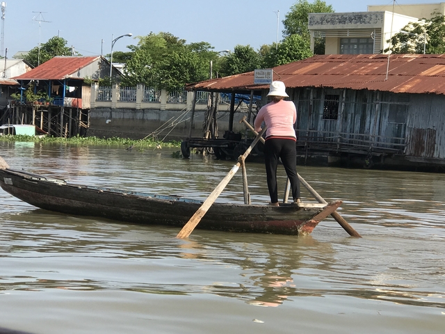 A person rowing a traditional wooden boat in a river.