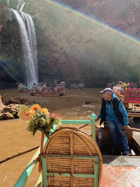       Rotated image of a man on a boat with a waterfall and rainbow.
  