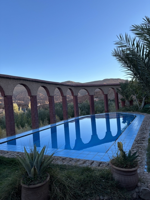 Swimming pool with arches and desert mountains in background.