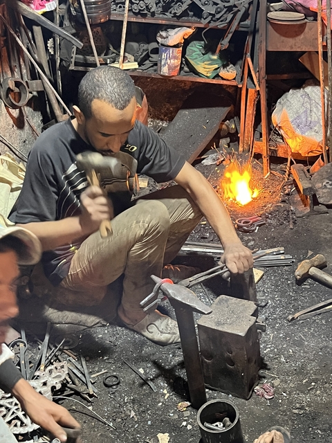       Blacksmith at work with fire and tools.
  