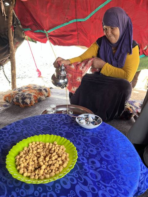       Woman preparing tea with a colorful table setting.
  