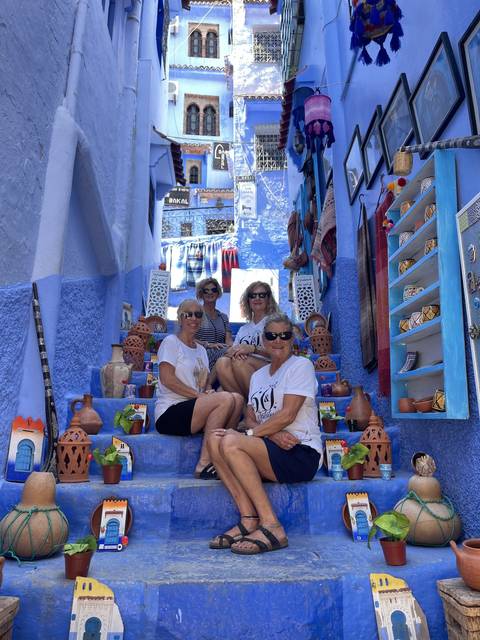       Tourists sitting on blue steps with handcrafted souvenirs around.
  