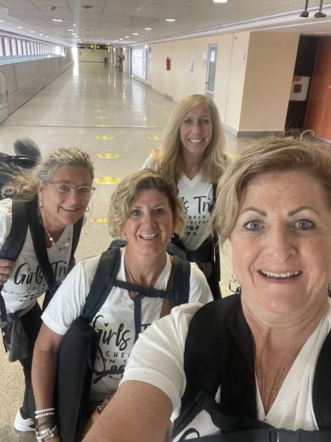 A group of women smiling and taking a selfie in an airport.