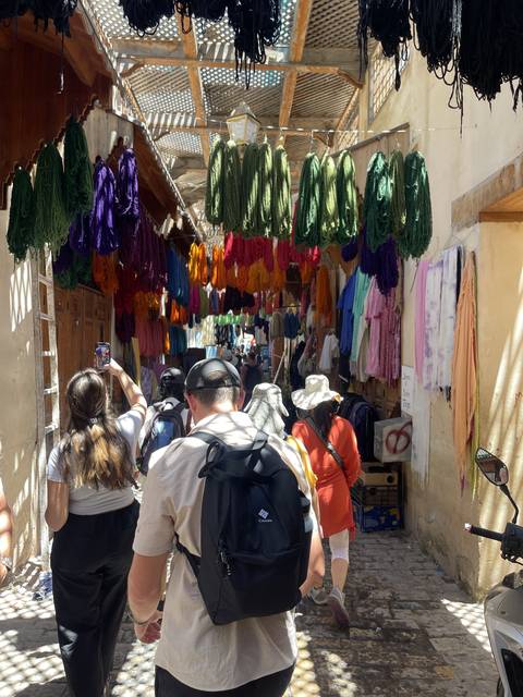       People exploring a colorful textile market.
  