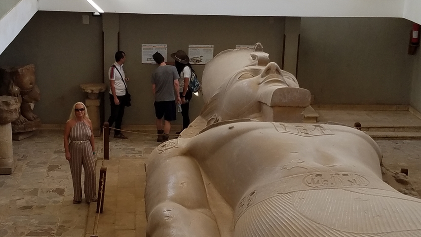 People viewing a large reclining statue indoors.