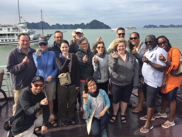Group of people posing on a boat with a scenic backdrop.