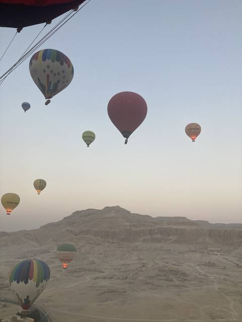       Hot air balloons floating in the sky over a desert landscape.
  