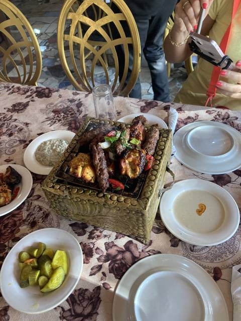       Table with various dishes including grilled meat and side dishes.
  