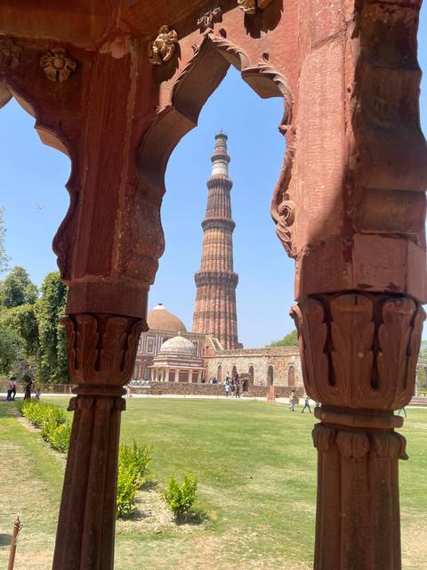       Minaret view through an ornate red stone arch.
  