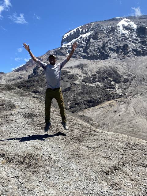 Person posing on a mountain slope with snow in the background.