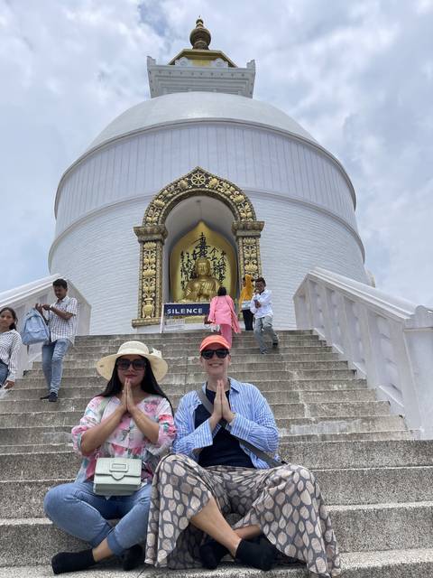       Two people posing near a white stupa.
  