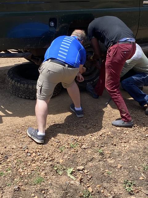       People changing a tire on a vehicle.
  