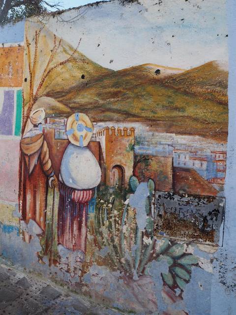 A weathered mural depicting historical scenes.