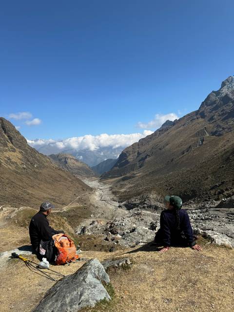 Two people enjoying a hike on a rocky landscape with mountains.