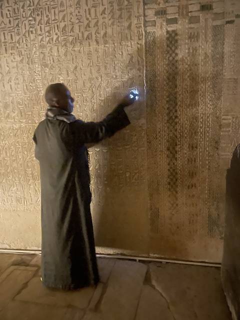       Person examining ancient Egyptian hieroglyphs on a wall.
  