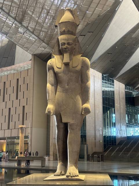 Statue of an ancient Egyptian figure inside a modern building.