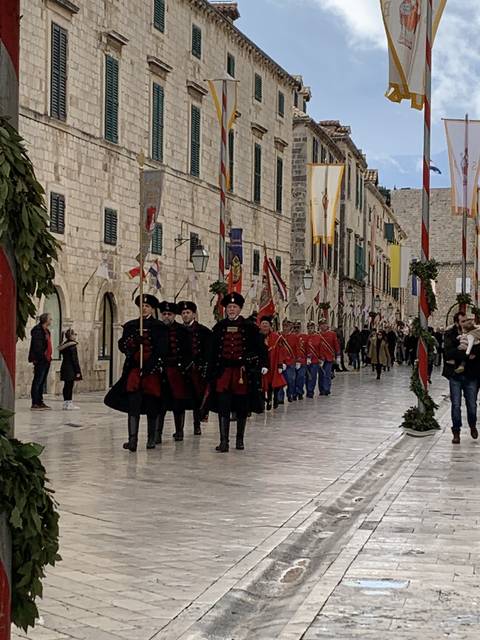       Parade in a historical street with people in costumes.
  