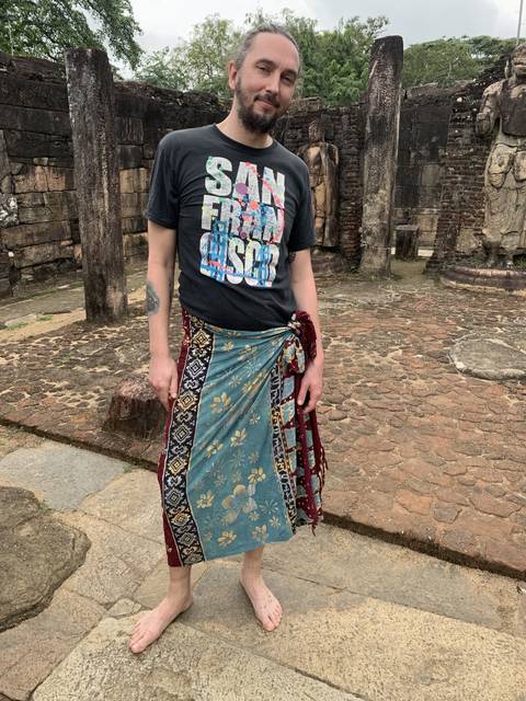 A person wearing a traditional sarong in an ancient stone setting.