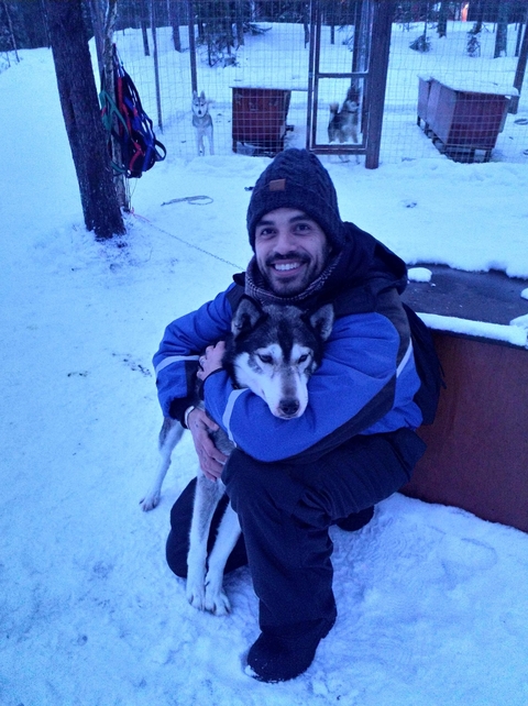 Person hugging a husky in a snowy environment.