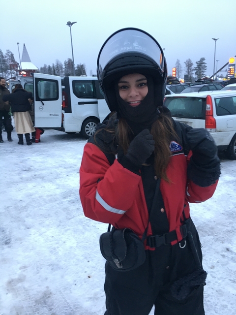 Person in a winter jacket standing by vehicles in the snow.